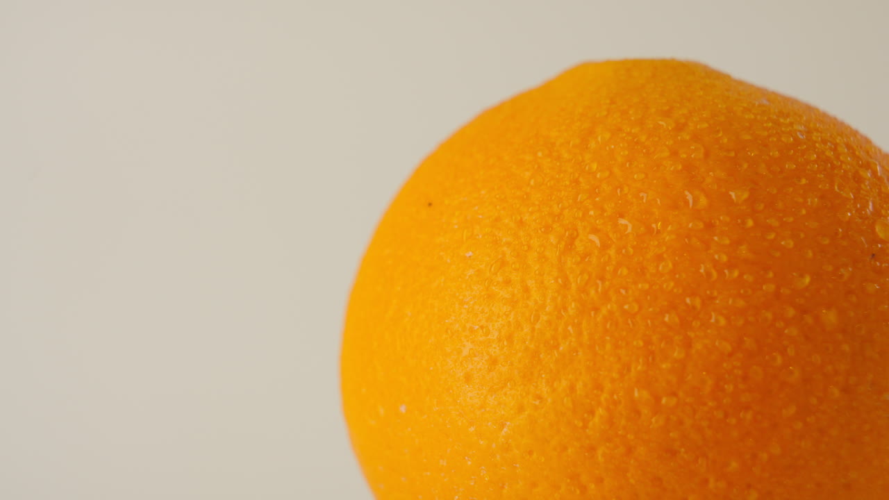 primer plano de una naranja húmeda giratoria cubierta con gotas de agua