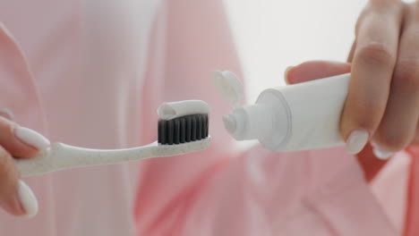 woman applying toothpaste to toothbrush