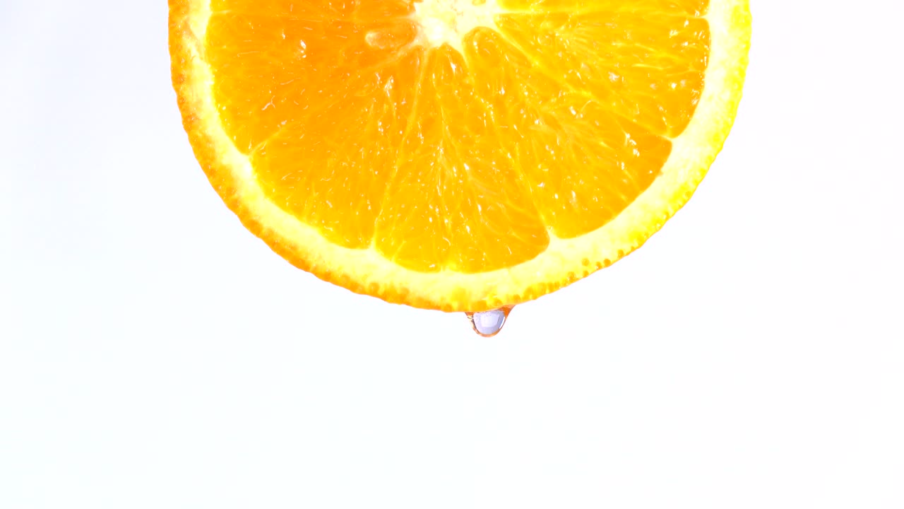 acqua o oli che cadono su una fetta di arancia, frutta per la dieta e il cibo sano