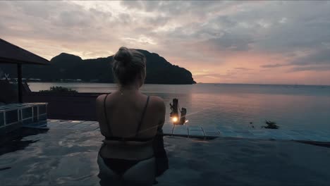 girl in pool overlooking koh pi pi sunset