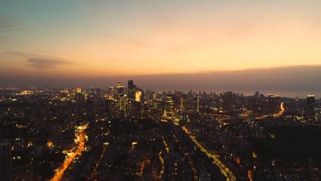 aerial view above tel aviv at night time sunset, city lights in the middle east at israel. skyline view of modern town landscape with business district, high buildings real estate