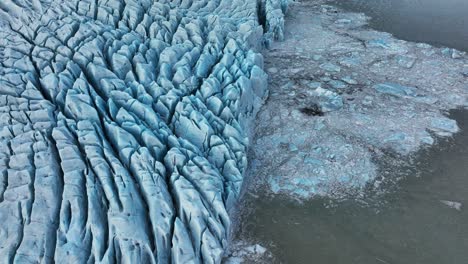 aerial view over textured ice formations of a melting glacier in iceland, at dusk