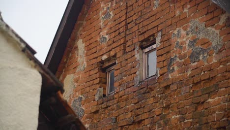 the weathered exterior of a rustic brick house with small windows, showcasing its aged and historical look