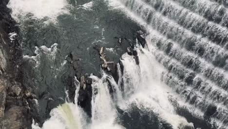 waterfall on the side of croton damn in new york, dark water and rocks