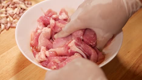 Hand-with-Glove-Mix-Pork-Loin-with-Marinated-Sauce-in-White-Bowl,-Close-Up-1