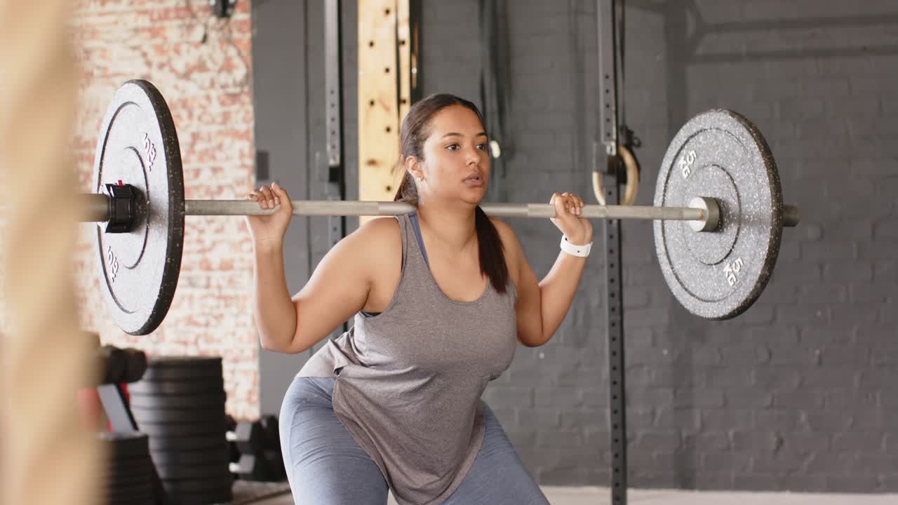 Gripping barbell and clearing rack, Hispanic woman performing back ...