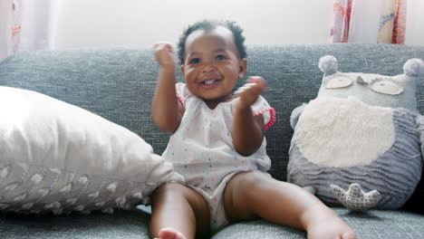 baby girl sitting on sofa and clapping at home