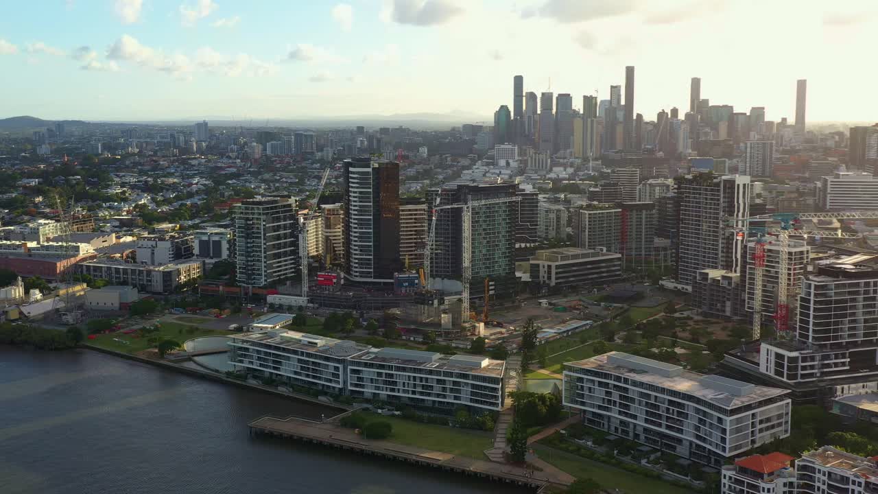 뉴스테드 강 테라스, 브리즈번 강을 따라 있는 해안가 주거 아파트 단지, 퀸즐랜드 수도 퀸즐랜드의 일몰 황금시간에 스카이라인의 시내 도시 경관을 따라 공중 드론이 날아갑니다.