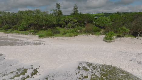 4K-Luftumlaufbahn-Eines-Australischen-Strandes-Mit-Meeresschaum,-Meeresschaum,-Strandschaum-Oder-Schaum,-Der-Durch-Die-Bewegung-Des-Meerwassers-Entsteht