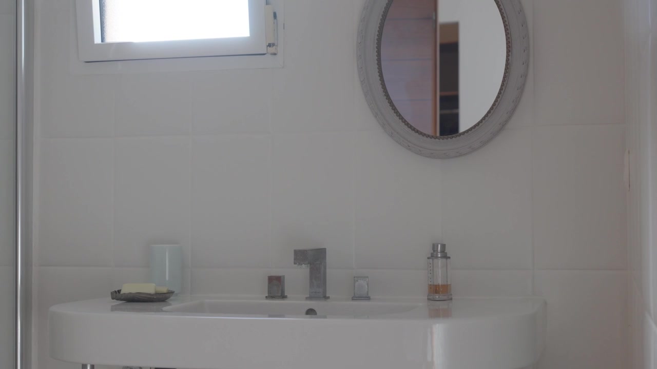 Lavandino, sapone e specchio in un bagno luminoso e moderno con luce naturale dalla finestra