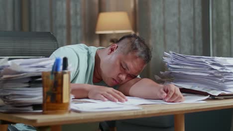 close up of fat asian man sleeping due to working hard with documents at the office