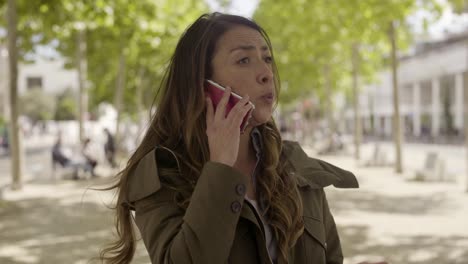 una joven mujer de negocios enojada hablando por teléfono afuera.