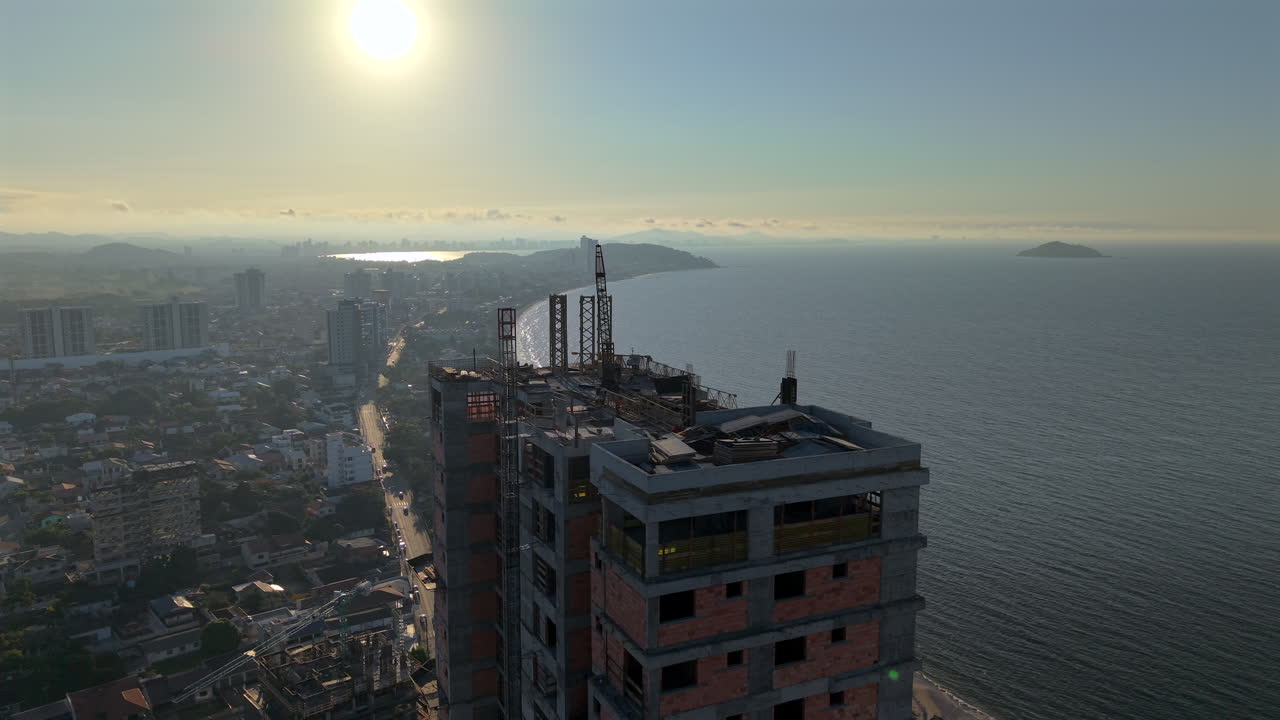Sunset light shining behind an urban high-rise building under a coastline environment at Penha, Santa Catarina, Brazil