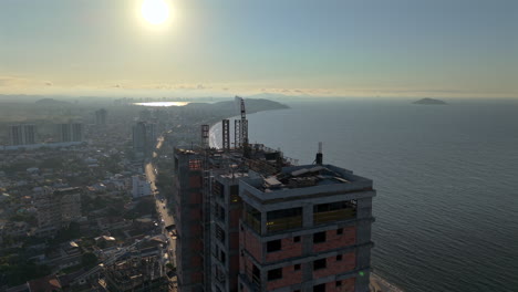 sunset light shining behind an urban high-rise building under a coastline environment at penha, santa catarina, brazil