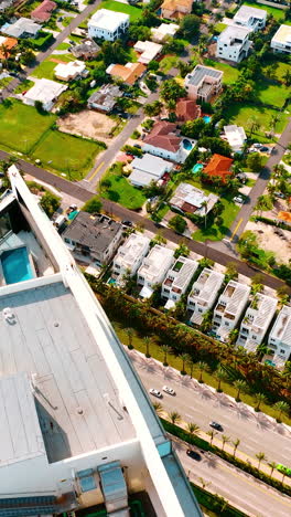 footage above the top of the high-rise building with a swimming-pool and lounge area on. busy highway at the foot of the house and low-rise architecture below. top view on miami beach, florida, usa. vertical video