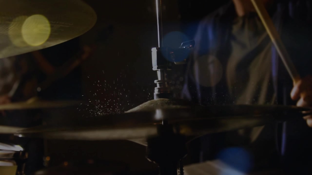 Batterista che abbassa la bacchetta sul charleston, alternando i colpi sui piatti, creando un groove con l'effetto splash del piatto