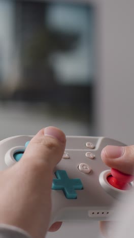 vertikal close-up video hände mann spielt videospiel controller bildschirm im hintergrund