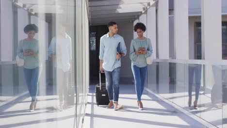 video of diverse businessman and businesswoman walking with suitcase and talking