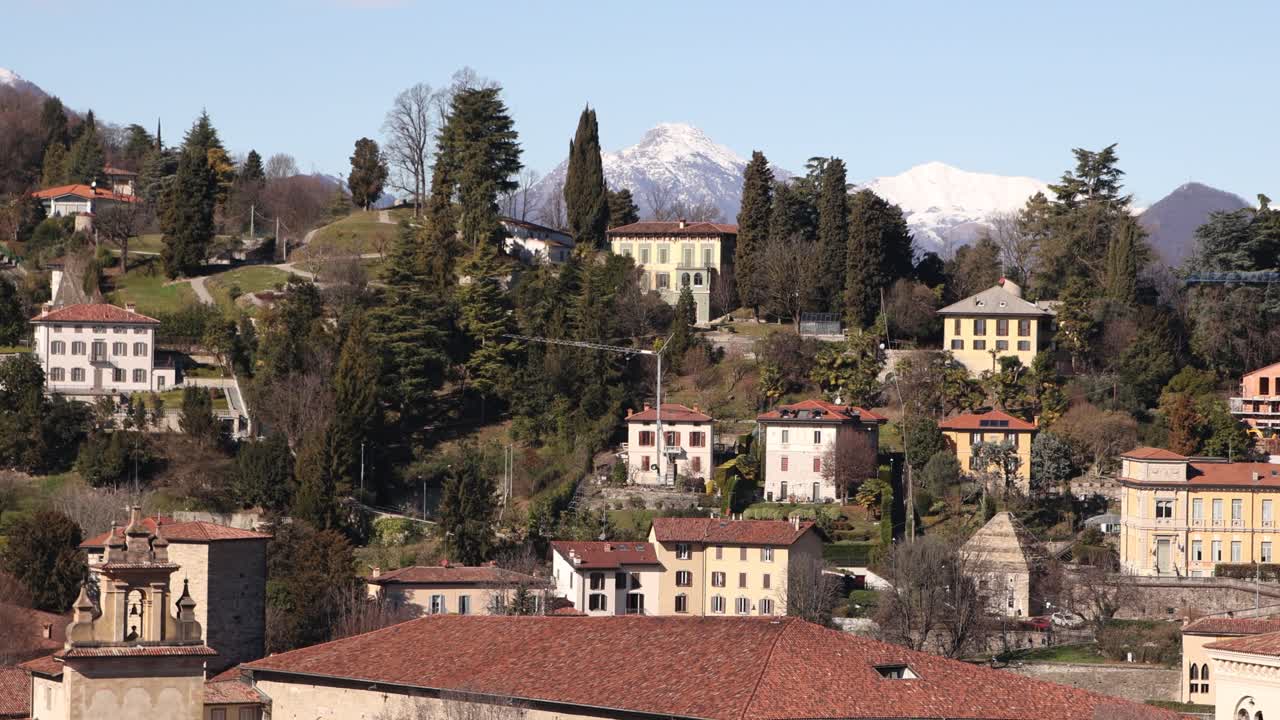 Prospettiva aerea del cuore storico di Bergamo, Italia, che cattura gli edifici densamente popolati con tetti rossi e le lontane pianure dell'Italia settentrionale.
