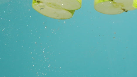 green apples sliced and falling into water