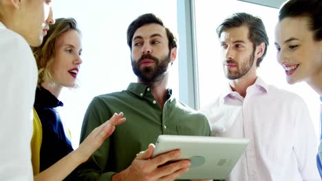 Smiling-business-team-discussing-over-digital-tablet