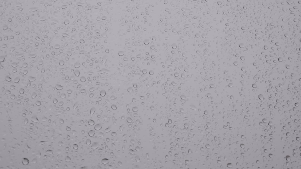 las gotas de lluvia ruedan lentamente hacia abajo en el panel de la ventana, fondo estático de primer plano