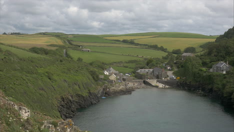 view of port quin, a charming coastal village with rolling fields as a backdrop, different pov, wide panning shot