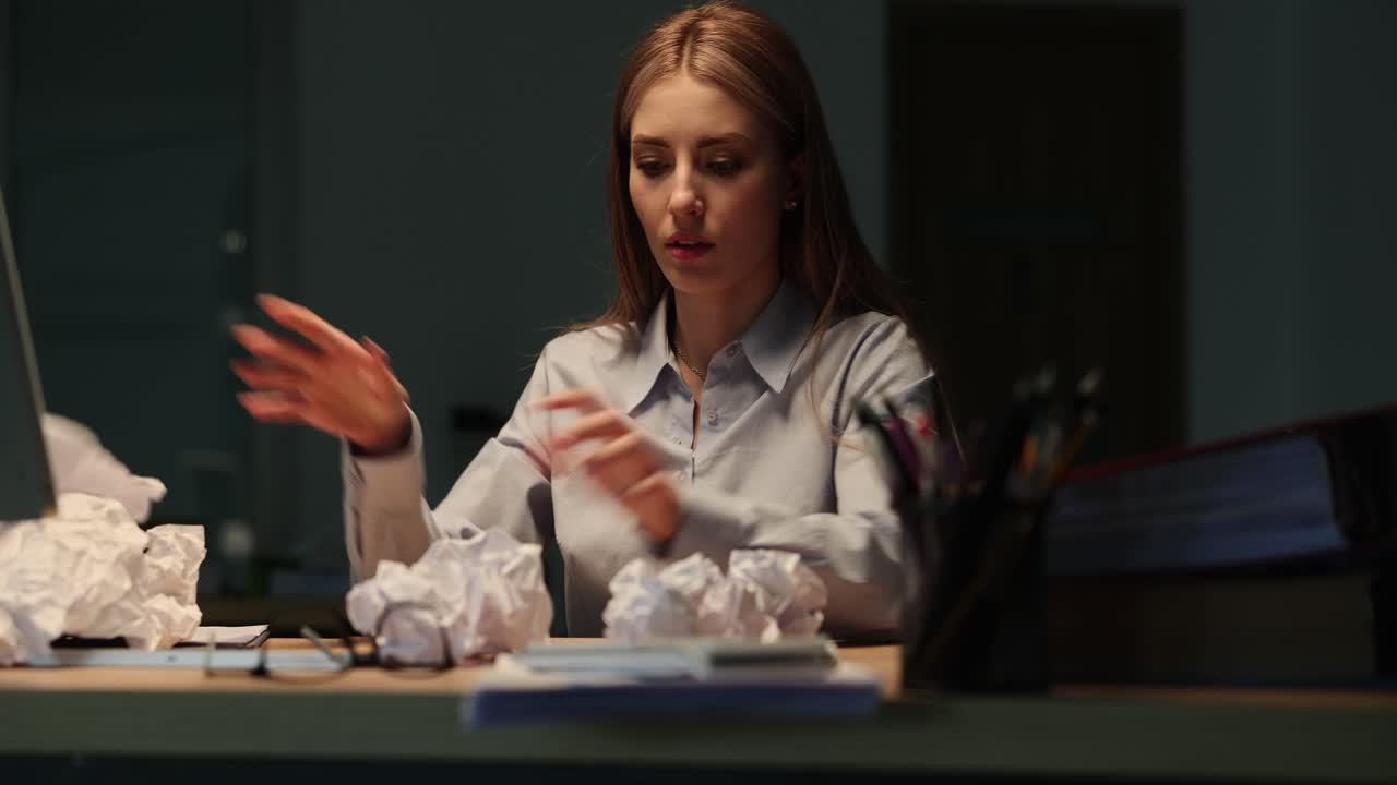 Frustrated woman with crumpled paper at desk