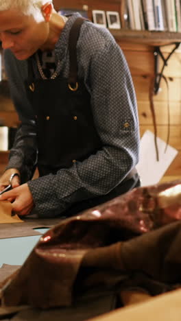 craftswoman cutting leather with scissors