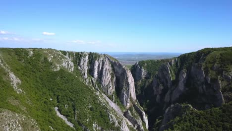 view from the top of cheile turzii, turda gorge, as drone pans right revealing the landscape and the horizon beyond the ravine