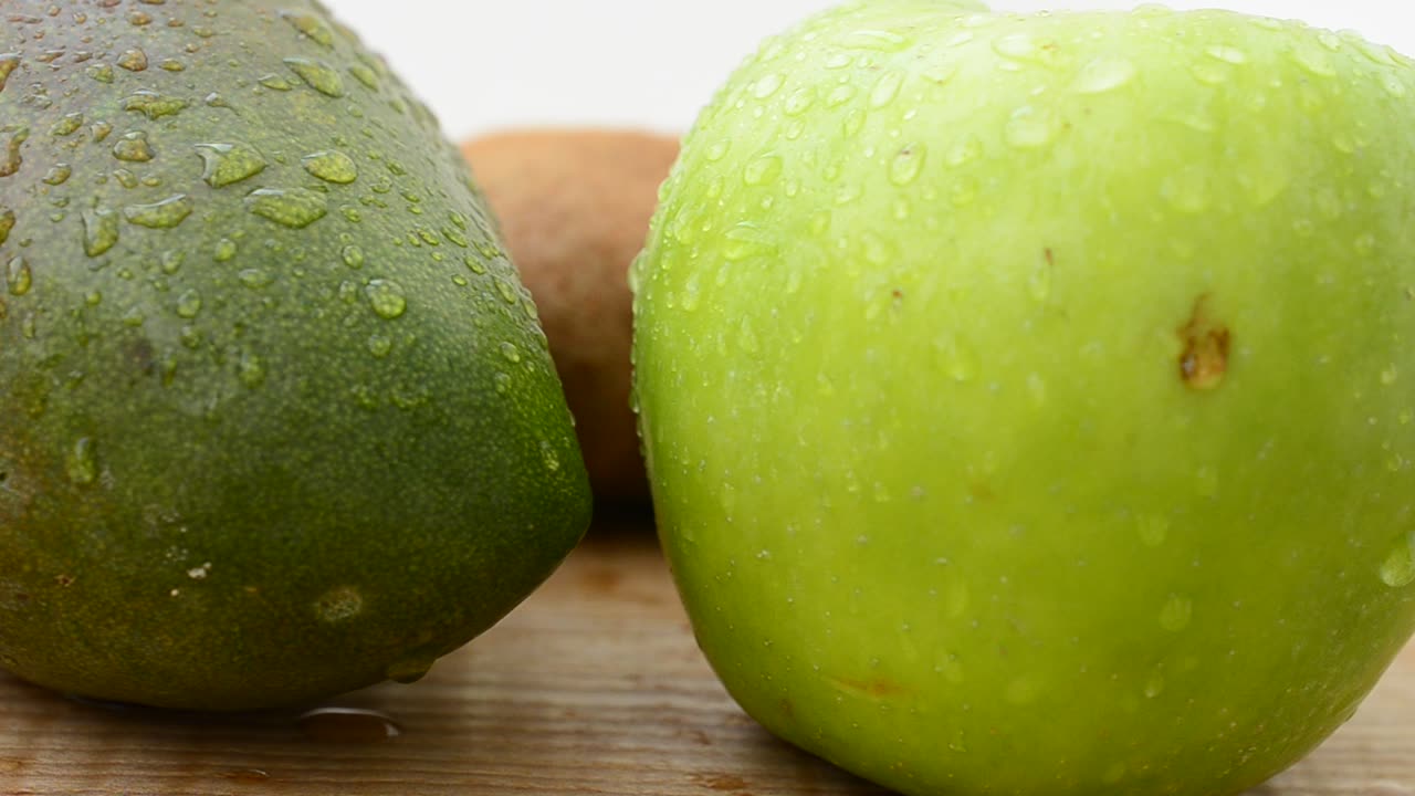 Frutta su un tagliere di legno. Mango, mela e kiwi. Riprese in movimento.