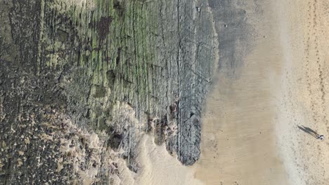 Top-down-shot-of-a-couple-walking-together-along-Doughmore-Bay,-Ireland