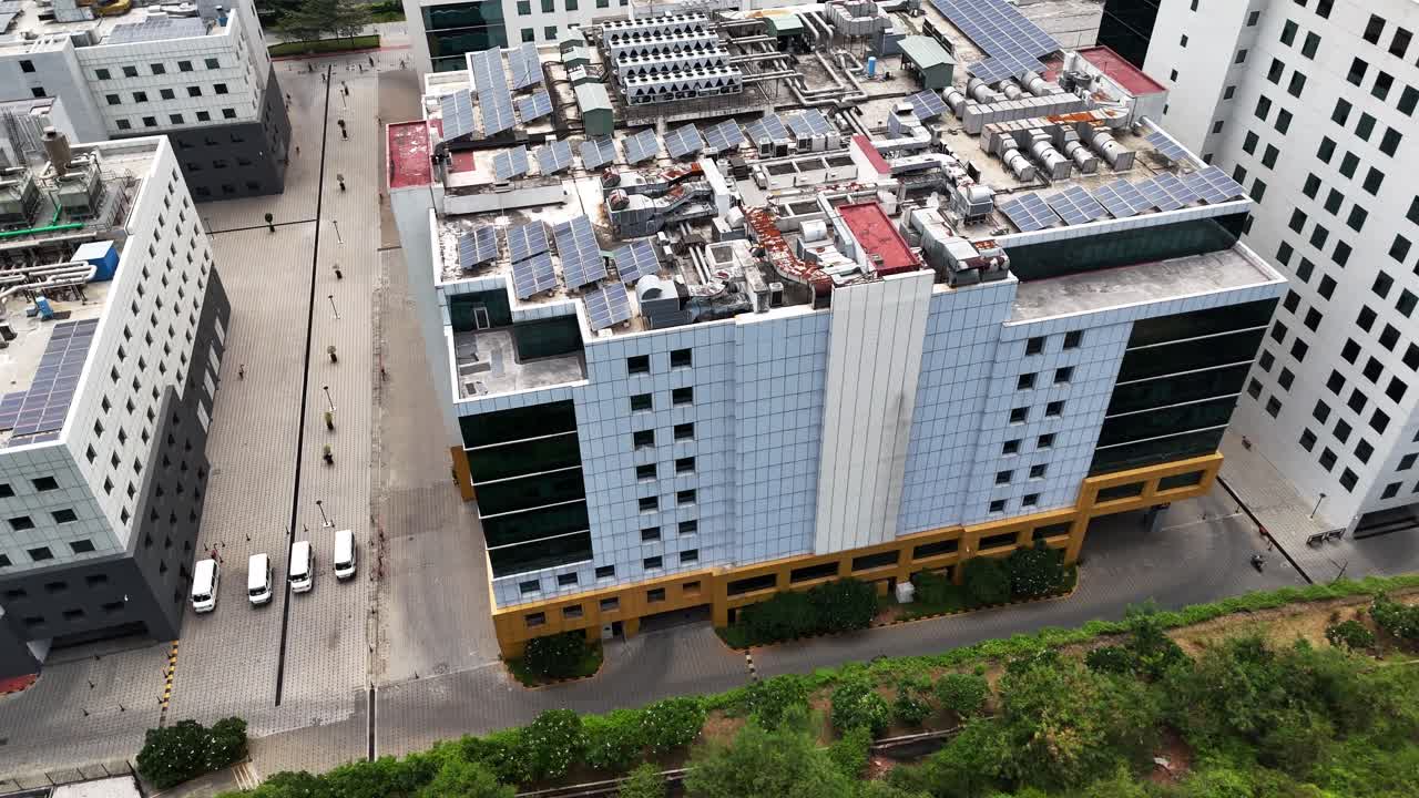 High-angle aerial view of a modern Sustainable Corporate Building featuring a striking facade and a roof covered with numerous solar panels. Represents green energy and corporate responsibility