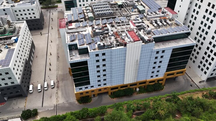 Vista aérea em ângulo alto de um edifício corporativo sustentável e moderno com uma fachada impressionante e um telhado coberto com vários painéis solares. Representa energia verde e responsabilidade corporativa.