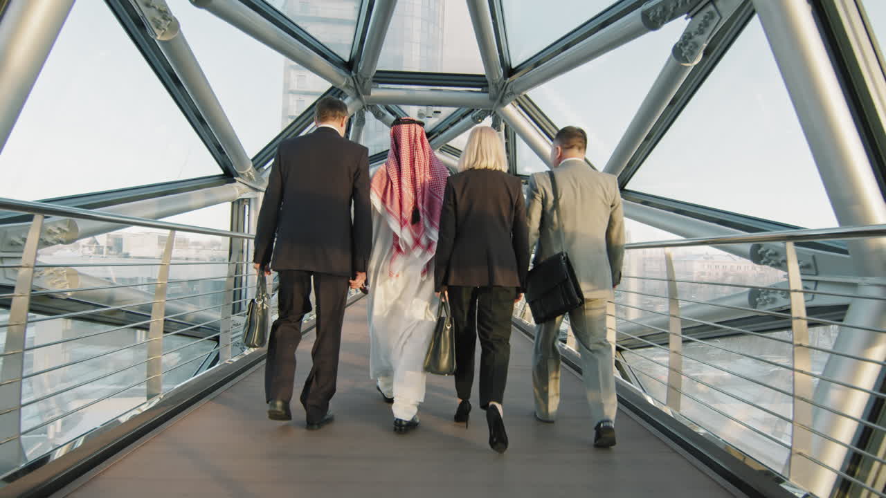 un equipo diverso de socios comerciales caminando a lo largo del puente de vidrio