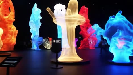 mesmerizing display of colorful abstract sculptures illuminated in a dark space, showcasing fluid designs and captivating visual patterns that engage the senses