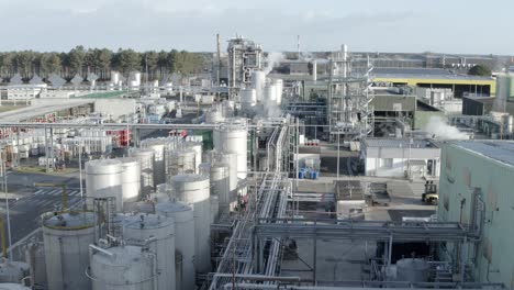aerial drone view through large industrial complex, showcasing numerous storage tanks, pipes, and steam emissions, castets, france