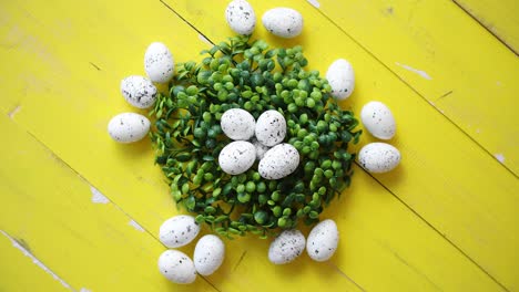 green decorative easter quail eggs wreath on yellow wooden table