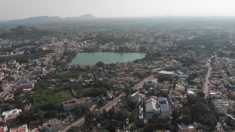 aerial view of natural pond in tiruvannamalai surrounded by city during sunny day in india