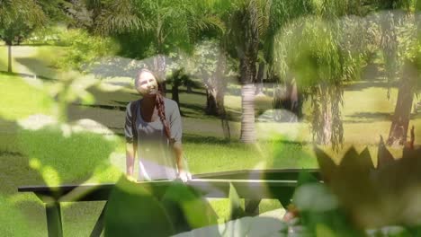 composite video of close up of leaves against caucasian woman walking in the garden