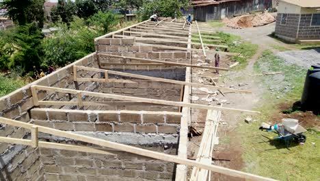 aerial shot of worker with hard hat and safety equipment installing and working on maintenance of photovoltaic panel system installed on home domestic roof top, urban landscape