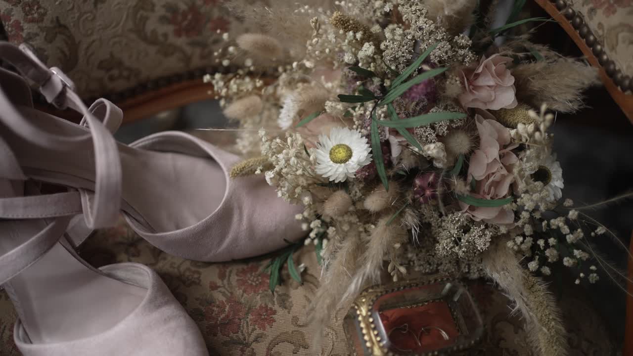 soft bridal shoes with rustic bouquet resting on elegant vintage upholstered chair