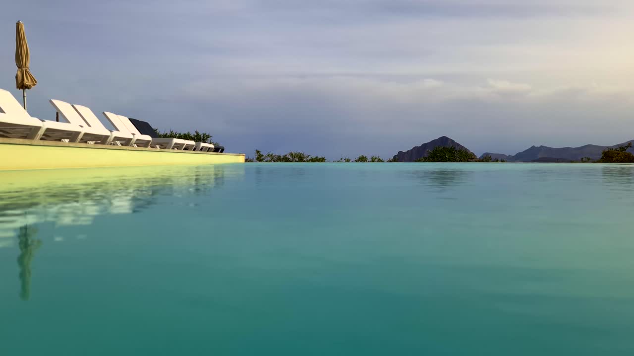 몬테 코파노를 배경으로 한 시칠리아 럭셔리 홀리데이 호텔의 인피니티 수영장의 낮은 각도 수면 포브