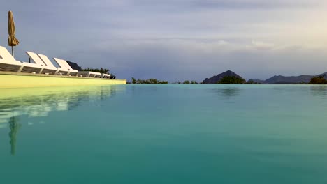 ángulo bajo de la superficie del agua pov de la piscina infinita en un hotel de vacaciones de lujo siciliano con monte cofano en segundo plano