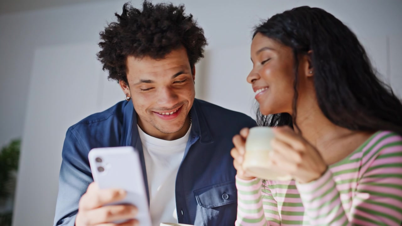 Casal pela manhã olhando o celular em casa. Pessoas alegres assistindo a um vídeo divertido