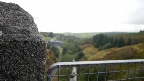 heavy stone wall metal barrier fence overlooking welsh valley countryside dolly right