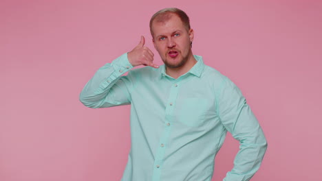 Cheerful-one-man-in-shirt-looking-at-camera-doing-phone-gesture-like-says-hey-you-call-me-back