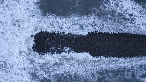 giant waves overflooding black basalt rocks on vi kurfjara beach,iceland,aerial top down