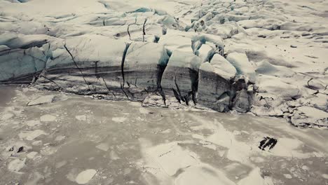 Glacier-tongue-in-Iceland-filmed-by-drone-with-different-cinematic-movements,-showing-a-cloudy,-dramatic-concept-in-wintery-conditions