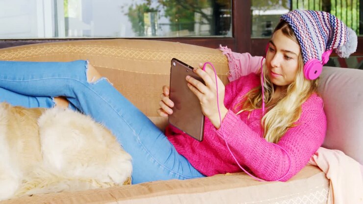 Woman with her dog listening music on sofa 4k